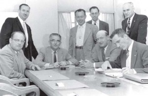 With L. L. “Mitch” Mitchell (seated right) as his chief  negotiator, Weakley (standing left) laid the  foundation for the  labor agreement with PG&E, now recognized as setting the  standard for wages and beneﬁts in the  utility industry