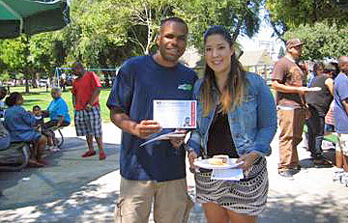 Local 1245 members Steve Gallow, left, and Jennifer Gray circulate “No on Proposition 32” cards at the EWMC picnic.