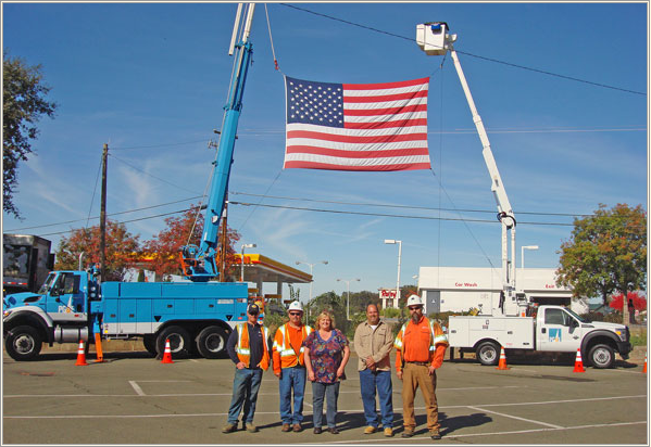 Helping hoist the flag to honor veteran Doug Harris are, from left: Lineman Mike Devlin, Electric Crew Foreman Dan Hernandez, Operating Clerk Lori Mobley, Supervisor Gino Rinaldi, and Lineman Travis Hyland.