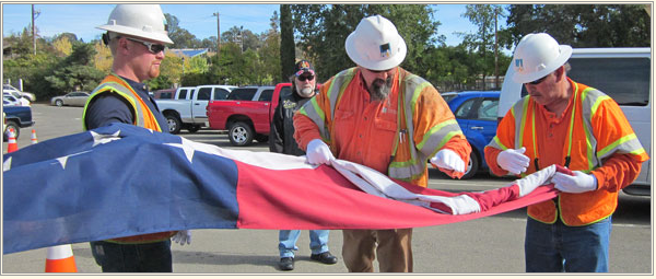 Lineman Travis Hyland, middle, shows the proper way to fold the flag. Hyland is a veteran and a 15-year IBEW member.