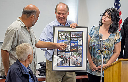 Mike studies the poster honoring his service to the union. From left: President Mike Davis, Grimm, Business Manager Tom Dalzell, former Advisory Council member Michelle Benuzzi. 