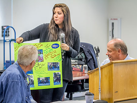 IBEW 1245 Organizer Jennifer Gray holds up the Thank You card given to IBEW 1245 by the OUR Walmart campaigners. Looking on are President Mike Davis, left, and Business Manager Tom Dalzell.