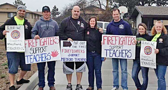 IBEW 1245 Organizing Stewards Michael Musgrove, left, and Kristen Rasmussen, right, joined union firefighters on the picket line on Feb. 13 in solidarity with striking teachers in Medford, OR.