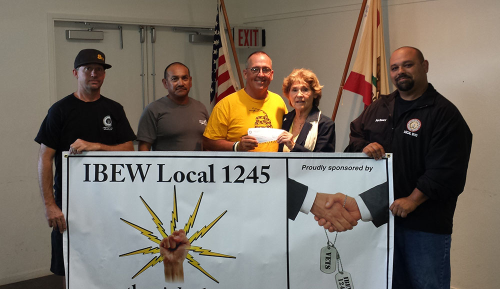 IBEW 1245 members (from left) Shawn Wynne, Jaime Tinoco, John Daniel and Bobby Garcia present the donation to Fallen Warrior Project committee member Laurie Lane (center). 
