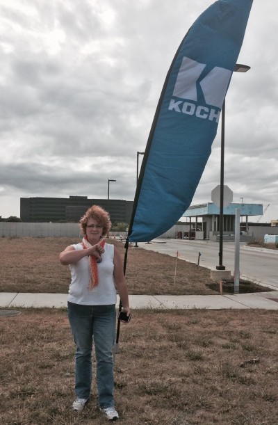 Kristen Rasmussen gives a “thumbs down” at the entrance to the Koch Industries compound in Wichita, KS.