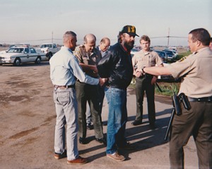Strike coordinator Dean Gurke is hauled away in handcuffs after using his car to block Asplundh trucks. IBEW 1245 Archive Photo by Pete Colbert