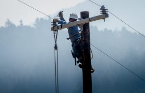 An IBEW lineman repairs a utility pole that was destroyed by a wildfire