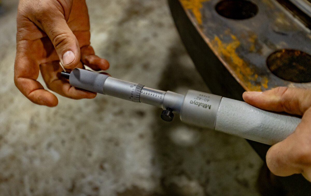 A micrometer is used to confirm exact tolerances on a massive drum component before reassembly—where even the smallest measurement can have major consequences.