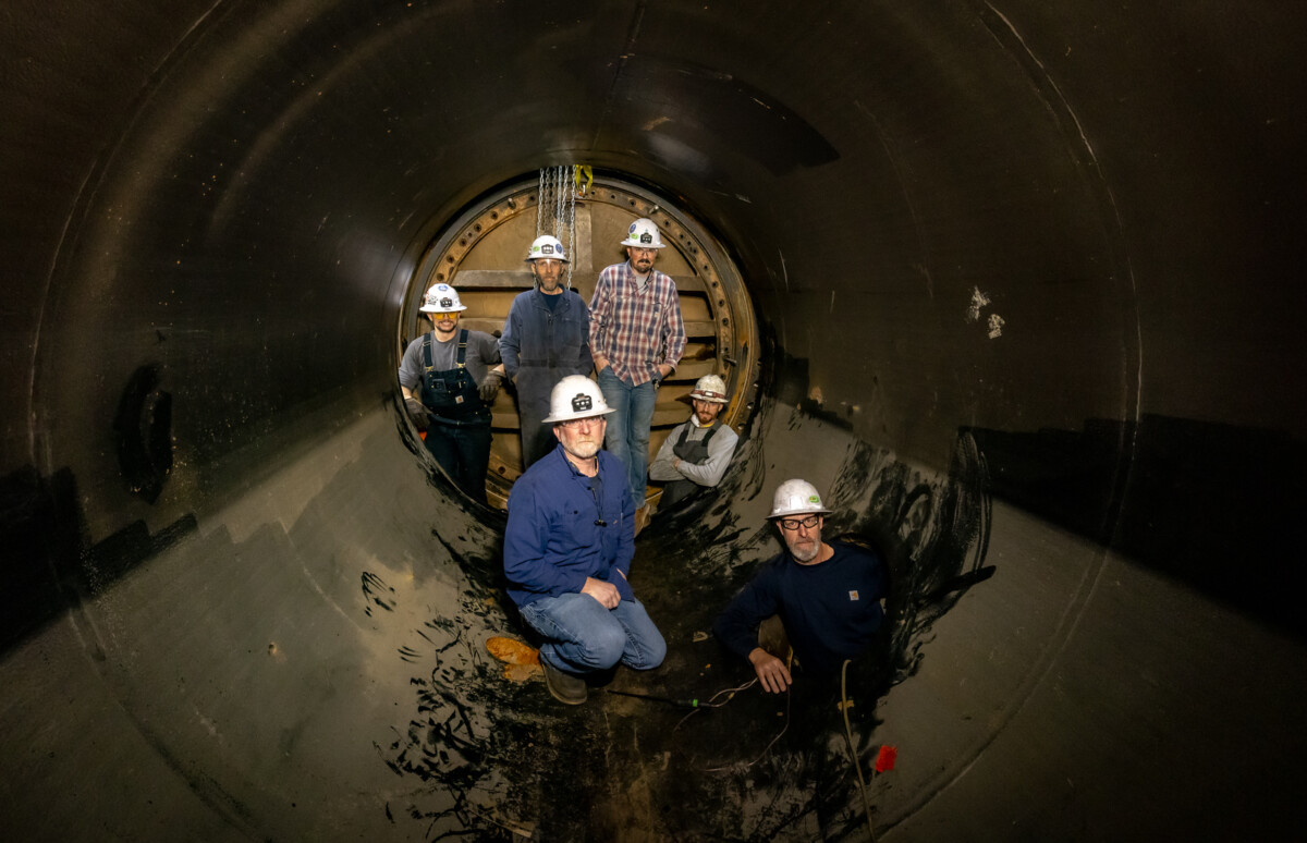 Inside one of Colgate’s massive steel pipes, IBEW 1245 hydro mechanics pause during maintenance work.
